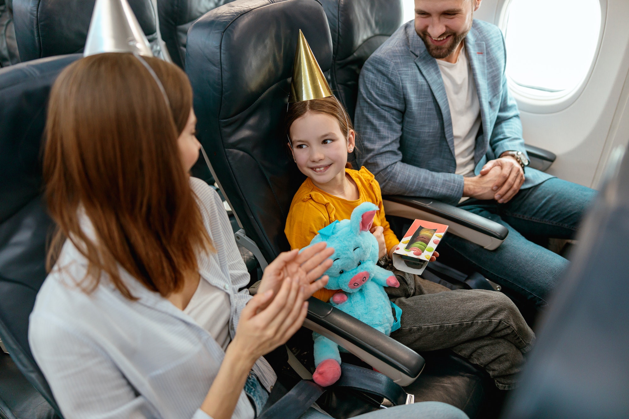 Happy parents celebrating kid birthday in airplane